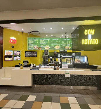 Cow N Potato Food Bar service counter with lit menu boards and the COW N POTATO sign